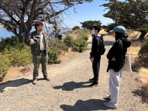 Photo of three people talking outside.