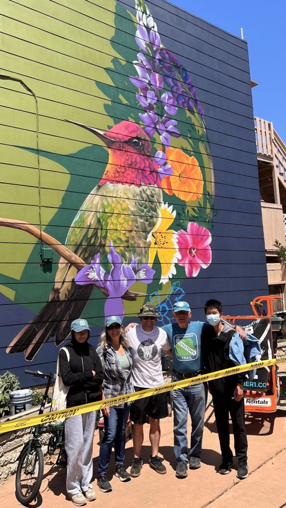 Photo of people in front of a mural painted on a building.